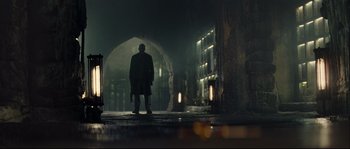 Movie still from “Empire of the Wolves” (2005), directed by Chris Nahon – A man standing in the dark in front of an archway; Wide shot, Low angle