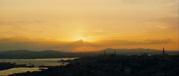 Movie still from “Empire of the Wolves” (2005), directed by Chris Nahon – The sun is setting over a large body of water; Extreme Wide shot, Low angle