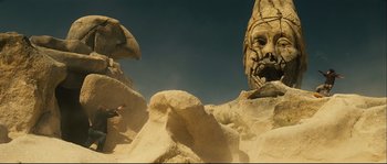 Movie still from “Empire of the Wolves” (2005), directed by Chris Nahon – A bird flying near a rock formation with a face on it's face; Extreme Wide shot, Low angle