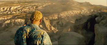 Movie still from “Empire of the Wolves” (2005), directed by Chris Nahon – A man standing on top of a mountain looking at the sky; Wide shot, High angle