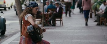 Movie still from “The Pursuit of Happyness” (2006), created by Frank Darabont – A woman sitting on a bench playing a guitar; Medium shot, Over the shoulder angle