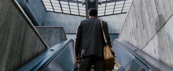 Movie still from “The Pursuit of Happyness” (2006), created by Frank Darabont – A man in a business suit is riding an escalator; Wide shot, Low angle