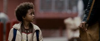 Movie still from “The Pursuit of Happyness” (2006), created by Frank Darabont – A little boy in a brown jacket is standing outside; Close Up shot, Over the shoulder angle