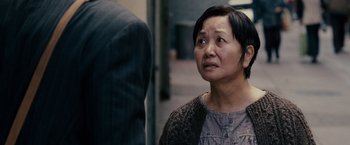 Movie still from “The Pursuit of Happyness” (2006), created by Frank Darabont – An older woman is standing in front of a man; Close Up shot, Over the shoulder angle