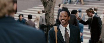 Movie still from “The Pursuit of Happyness” (2006), created by Frank Darabont – A man in a suit and tie standing in front of a crowd; Medium shot, Over the shoulder angle