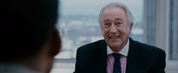 Movie still from “The Pursuit of Happyness” (2006), created by Frank Darabont – An older man wearing a suit and tie smiling; Close Up shot, Over the shoulder angle