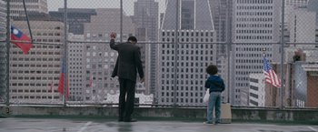 Movie still from “The Pursuit of Happyness” (2006), created by Frank Darabont – A man and a child standing in front of a wire fence; Wide shot, Over the shoulder angle