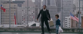 Movie still from “The Pursuit of Happyness” (2006), created by Frank Darabont – A man in a suit and tie holding a paper bag walking next to a child; Wide shot, Low angle