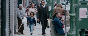 Movie still from “The Pursuit of Happyness” (2006), created by Frank Darabont – A man walking down the street with a young boy; Medium shot, Over the shoulder angle