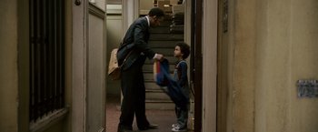 Movie still from “The Pursuit of Happyness” (2006), created by Frank Darabont – A man in a suit handing a bag to a young boy; Medium shot, Over the shoulder angle