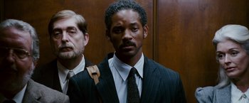 Movie still from “The Pursuit of Happyness” (2006), created by Frank Darabont – A man in a suit standing next to another man in a suit; Close Up shot, Low angle