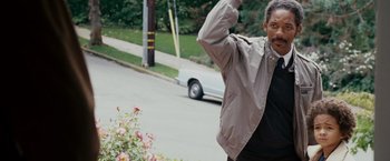 Movie still from “The Pursuit of Happyness” (2006), created by Frank Darabont – A man standing on the side of a road waving; Medium shot, Low angle