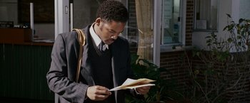 Movie still from “The Pursuit of Happyness” (2006), created by Frank Darabont – A man in a suit and tie looking at a piece of paper; Close Up shot, Over the shoulder angle