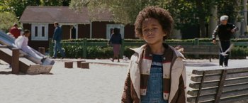 Movie still from “The Pursuit of Happyness” (2006), created by Frank Darabont – A young boy standing in the sand in front of a building; Close Up shot, Over the shoulder angle