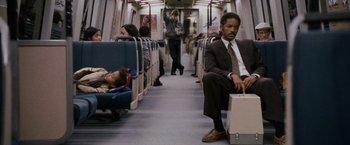 Movie still from “The Pursuit of Happyness” (2006), created by Frank Darabont – A man sitting on a train next to a sleeping woman; Wide shot, Low angle