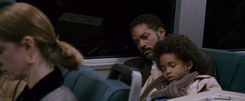 Movie still from “The Pursuit of Happyness” (2006), created by Frank Darabont – A man sitting next to a child on a bus; Close Up shot, Low angle