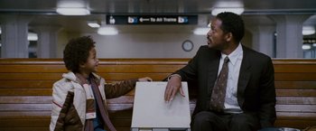Movie still from “The Pursuit of Happyness” (2006), created by Frank Darabont – A man sitting next to a young boy on a bench; Medium shot, Over the shoulder angle