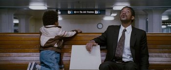 Movie still from “The Pursuit of Happyness” (2006), created by Frank Darabont – A man sitting on a bench next to a young boy; Medium shot, Over the shoulder angle