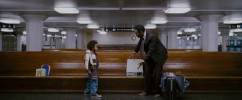 Movie still from “The Pursuit of Happyness” (2006), created by Frank Darabont – A man in a suit and tie holding a suitcase and a boy in a jacket; Wide shot, Over the shoulder angle