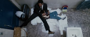 Movie still from “The Pursuit of Happyness” (2006), created by Frank Darabont – Two men are laying on the floor in a bathroom; Medium shot, Overhead angle