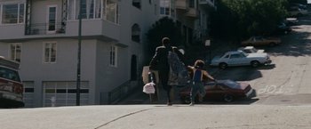 Movie still from “The Pursuit of Happyness” (2006), created by Frank Darabont – A woman and a child walking down a street; Wide shot, High angle