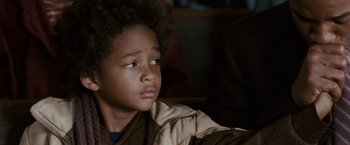 Movie still from “The Pursuit of Happyness” (2006), created by Frank Darabont – A young boy sitting in front of a window looking sad; Close Up shot, High angle