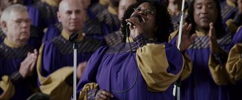 Movie still from “The Pursuit of Happyness” (2006), created by Frank Darabont – A woman in a choir singing into a microphone; Close Up shot, Low angle
