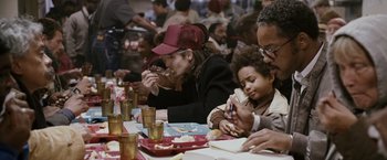 Movie still from “The Pursuit of Happyness” (2006), created by Frank Darabont – A group of people sitting at a table eating food; Medium shot, Over the shoulder angle