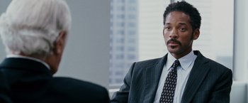 Movie still from “The Pursuit of Happyness” (2006), created by Frank Darabont – A man wearing a suit and tie sitting in front of another man wearing a suit and tie; Close Up shot, Over the shoulder angle