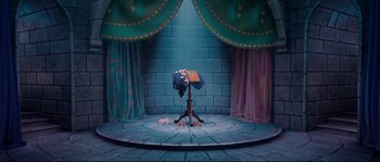 Movie still from “Enchanted” (2007), directed by Kevin Lima – A stage with a blue curtain and a stage with a blue curtain and a stage with a stage with a blue curtain and a stage with a blue; Wide shot, High angle