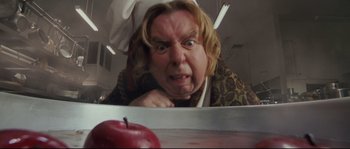 Movie still from “Enchanted” (2007), directed by Kevin Lima – A man with blonde long hair is looking at an apple on a table; Close Up shot, Overhead angle