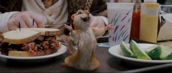 Movie still from “Enchanted” (2007), directed by Kevin Lima – A hamster standing on its hind legs in front of plates of food; Medium shot, High angle
