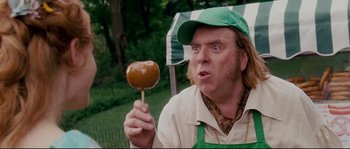 Movie still from “Enchanted” (2007), directed by Kevin Lima – A man holding an apple on top of a wooden stick; Close Up shot, Over the shoulder angle