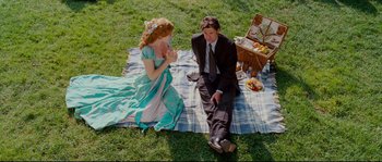 Movie still from “Enchanted” (2007), directed by Kevin Lima – A man and a woman sitting on a blanket on the grass; Wide shot, High angle