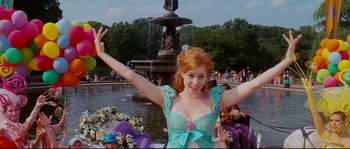 Movie still from “Enchanted” (2007), directed by Kevin Lima – A woman with red hair and a blue dress is in front of a fountain; Medium shot, Low angle