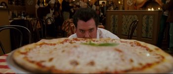 Movie still from “Enchanted” (2007), directed by Kevin Lima – A man is looking at a large pizza on the table; Close Up shot, Over the shoulder angle