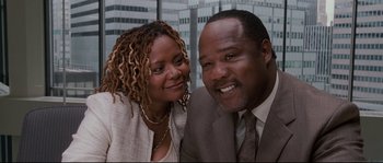 Movie still from “Enchanted” (2007), directed by Kevin Lima – A man and a woman posing for a picture in front of some buildings; Close Up shot, Low angle