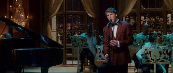 Movie still from “Enchanted” (2007), directed by Kevin Lima – A man singing into a microphone in front of a piano; Medium shot, Over the shoulder angle