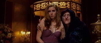Movie still from “Enchanted” (2007), directed by Kevin Lima – A woman in a strapless purple dress and a man in a black robe; Medium shot, Over the shoulder angle