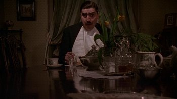 Movie still from “Enchanted April” (1991), directed by Mike Newell – A man sitting at a table with a plate in front of him; Medium shot, High angle