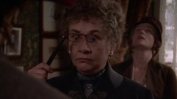 Movie still from “Enchanted April” (1991), directed by Mike Newell – An older woman is holding a pair of glasses; Close Up shot, Over the shoulder angle