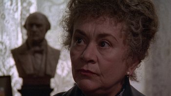 Movie still from “Enchanted April” (1991), directed by Mike Newell – An older woman with curly brown hair looking at the camera; Close Up shot, Over the shoulder angle