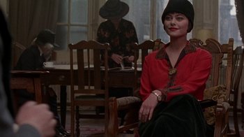 Movie still from “Enchanted April” (1991), directed by Mike Newell – A woman sitting in a chair in front of a table; Medium shot, Over the shoulder angle