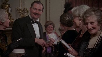 Movie still from “Enchanted April” (1991), directed by Mike Newell – A group of people standing in a room; Medium shot, Over the shoulder angle