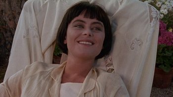 Movie still from “Enchanted April” (1991), directed by Mike Newell – A woman laying on the ground smiling for the camera; Close Up shot, High angle