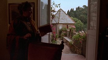 Movie still from “Enchanted April” (1991), directed by Mike Newell – An older woman standing on the porch of a house; Wide shot, Low angle