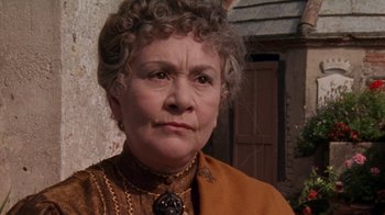 Movie still from “Enchanted April” (1991), directed by Mike Newell – An older woman wearing an orange jacket and a necklace; Close Up shot, Low angle