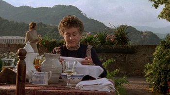 Movie still from “Enchanted April” (1991), directed by Mike Newell – An older woman sitting at a table with a glass of wine; Medium shot, High angle