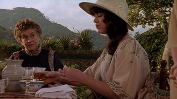Movie still from “Enchanted April” (1991), directed by Mike Newell – A woman sitting at an outdoor table with a glass of wine; Medium shot, Over the shoulder angle