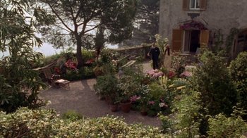 Movie still from “Enchanted April” (1991), directed by Mike Newell – A man and a woman walking through a garden; Extreme Wide shot, High angle